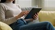 © Vadym - Woman relaxes on sofa using tablet computer. Female browses online content on digital device while sitting indoors. Casual home lifestyle scene with person and tech.