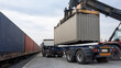 © Elena - Cargo container lifted by industrial crane onto a truck beside a freight train. Intermodal transport and dry bulk logistics at a modern terminal.