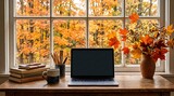Cozy desk featuring modern laptop books and pencil cup placed near window overlooking autumn landscape perfect for creative home office work space and academic study atmosphere.