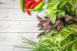 © Anna - Red and green peppers with fresh basil, arugula and green onions on a white wooden studio background create a colorful summer harvest scene with a lively mood