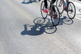 Cyclists Riding Road Bikes with Long Shadows Cast on Asphalt Street
