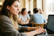 © Pixel-Shot - Remote work and digital nomad lifestyle, young woman working on laptop in a busy cafe or coworking space