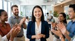 © Munjamil - Diverse business team applauding and cheering for a successful smiling female leader in a modern office