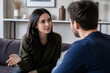 © Anastasiia - A woman in a green sweater and a man in a blue shirt are engaged in an intimate conversation indoors.