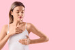 © Pixel-Shot - Young woman checking her breast on pink background. Breast cancer awareness concept