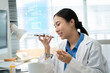 © Yingyaipumi - Asian female doctor using a smartphone in a hospital,interacting with a virtual assistant or AI chatbot.doctor reviews health data via ai agent,smart mirror technology,future technology