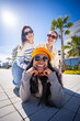 © CarlosBarquero - Vertical. Three female friends enjoy a playful pose outdoors in a bright modern neighborhood, creating a fun lifestyle portrait with friendship and sunny travel vibes.