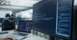 © Gorodenkoff - Close-up of a Computer Screen Showing Backend Program Code and Sql Database Query Next to a Laptop While an Unseen Software Developer Writes Scripts in a Busy Office With Diverse Engineers Nearby.
