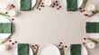 © Emre Akkoyun - Winter holiday dining table setup featuring plates, green napkins, candles, cranberries, and rosemary on a linen tablecloth