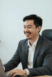 © Pixel-Shot - Successful business professional working on laptop, happy asian man smiling in modern office environment, corporate success and productivity