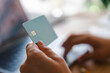 © Studio Marmellata - A person is holding a credit card while sitting in front of a laptop computer. They are performing an online transaction to make a secure payment from their home office.
