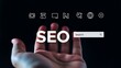 © MDMAHBUBUR - A human hand reaching towards a glowing digital seo search bar interface with various website optimization on a dark background setting