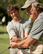 © Инна Харайшвили - Senior golfer teaching younger man golf swing on course