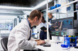 © DC Studio - Chemist in a biolab studies experiment data on a computer with fascination and curiosity, reading unusual biotechnology research results and an intriguing scientific discovery in medical research.