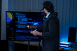 © ultramansk - South Asian male AI developer adjusts settings on a multi-monitor setup showing machine learning algorithms in a nighttime office.