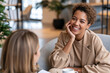 © lashkhidzetim - Warm smile lights up a relaxed conversation. Woman rests chin on hand, listening intently. Soft lighting highlights cozy, modern cafe setting. Comfortable seating suggests friendly, casual meeting