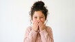 © sanchananipun - Close-up portrait of giggling young girl covering mouth with hand in shy playful moment on white background