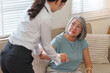 © Natee Meepian - Healthcare worker assisting senior Asian woman to stand up at home