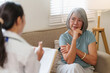 © Natee Meepian - Senior Asian woman consulting with doctor during home health checkup