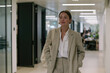 © Milos - A businesswoman dressed in a sleek beige suit walks through a sophisticated office, exuding confidence and style while reflecting a modern and professional atmosphere.