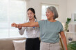 © Natee Meepian - Asian physical therapist helping senior woman with arm exercise at home