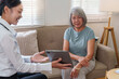 © Natee Meepian - Asian doctor showing digital tablet to senior patient during home healthcare consultation