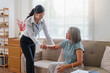 © Natee Meepian - Asian caregiver assisting senior woman sitting on couch at home for healthcare
