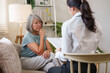 © Natee Meepian - Senior Asian woman talking to healthcare worker during medical consultation at home