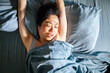 © Davor - Woman waking up and stretching in bed at home