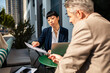 © Davor - Two business professionals reviewing documents at outdoor city cafe