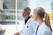© Davor - Two doctors walking and talking outside a modern hospital