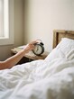 © Hungarian - Person Reaching for Black Vintage Alarm Clock at Seven AM in a Bright Minimalist Bedroom Setting