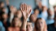 © The Little Hut - Close-up of a hand raised in a crowd, seeking attention or asking a question during a presentation or meeting