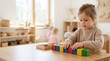 © Alva - A young girl playing with colorful wooden building blocks in a bright preschool classroom.