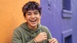 © xuxu - Portrait of happy teenage boy with purple curly hair laughing outdoors against graffiti wall. Joyful youth expression, positive emotion and generation z lifestyle concept