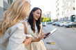 © Dexon Dee - Women sharing digital tablet content in city street