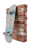 Worn wooden skateboard with light blue paint leaning against a rustic brick wall isolated on transparent background