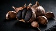 © Oleksandr - Dark gourmet black garlic bulbs, cloves artfully arranged on slate surface. Ingredient offers unique umami flavor for culinary creations, health benefits. Perfect for food blogs, restaurant menus.