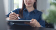 © tippapatt - Close up, asian business woman using stylus pen and digital tablet working at office with laptop on desk.