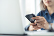 © tippapatt - Business woman using smartphone during online working on laptop, surfing the net, searching the information at office.