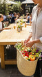 © pattaphorn - Person carries basket of fresh vegetables and flowers in vibrant co living community setting highlighting culture and connection