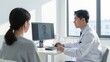 © Dono - Professional male doctor consulting with female patient during telemedicine video call on computer screen in modern bright clinic with natural window light and minimalist interior