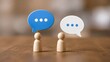 © Elite Studio - Two wooden figures facing each other with blue and white speech bubbles. Concept of business communication and corporate dialogue.