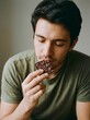 © utaem2022 - Close up of a man with beard eating chocolate piece savoring rich indulgence