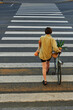 © Amor Burakova/Stocksy - Person walks across a crosswalk carrying bicycle