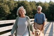© Andrii Zastrozhnov - Senior couple walking golden retriever on a wooden boardwalk in a green park for wellness banner and lifestyle background