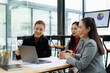 © David - Three asian business women collaborating and discussing project data on a laptop and monitor during a corporate meeting, showing teamwork, communication, and business success in the office