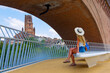 © M.studio - young woman sitting on bench under bridge admiring albi cathedral, tarn, france, travel and relaxation concept