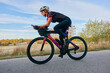 © .shock - Female Cyclist Riding Aerodynamic Road Bike Outdoors at Sunrise Training for Triathlon and Fitness