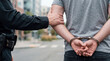 © ArtKa - Police officer holding the arm of a handcuffed man during an arrest on a city street, escorting the suspect. Concept of law enforcement, crime detention, criminal justice.